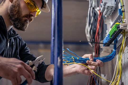 electricista con unos alicates cortando los cables que salen del cuadro